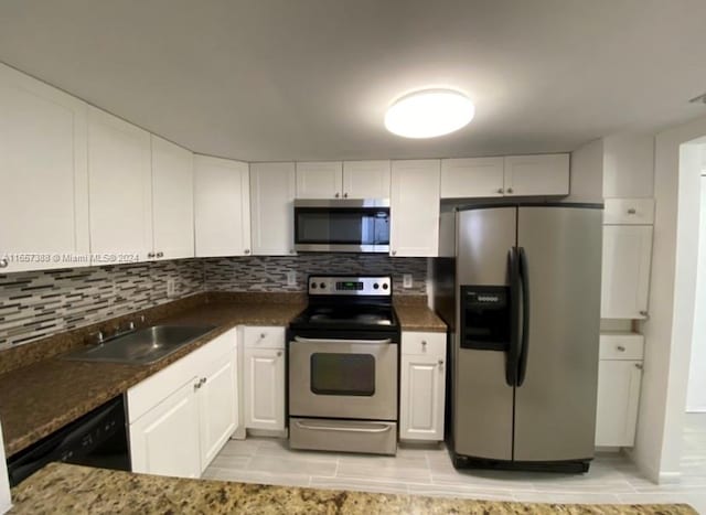 kitchen featuring dark stone countertops, appliances with stainless steel finishes, white cabinetry, sink, and decorative backsplash