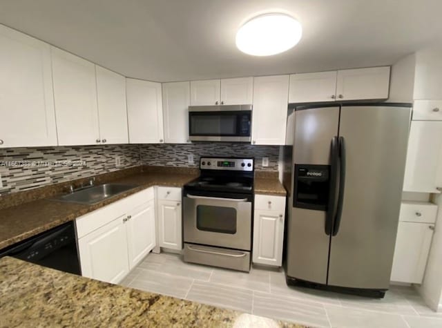 kitchen featuring dark stone counters, white cabinetry, tasteful backsplash, stainless steel appliances, and sink