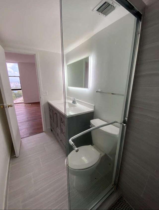 bathroom featuring a shower with shower door, wood-type flooring, toilet, and vanity