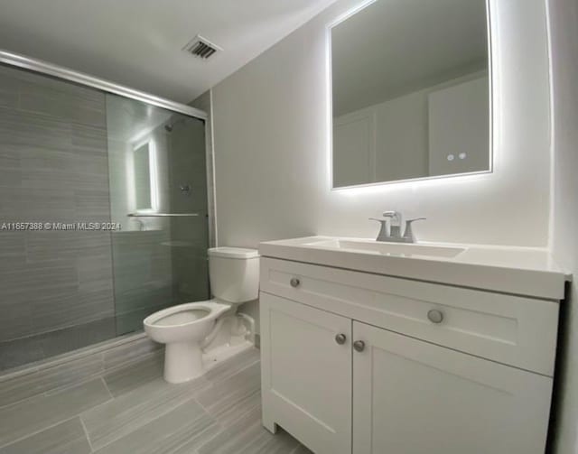 bathroom featuring walk in shower, toilet, and vanity