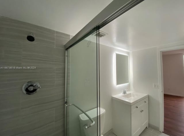 bathroom with a shower with shower door and vanity