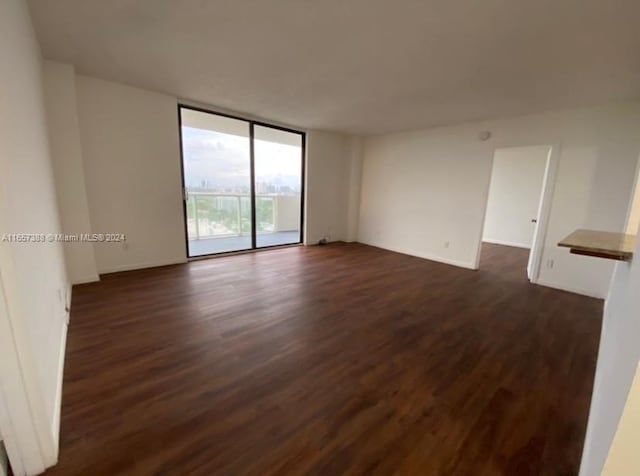 empty room featuring dark hardwood / wood-style flooring and a wall of windows