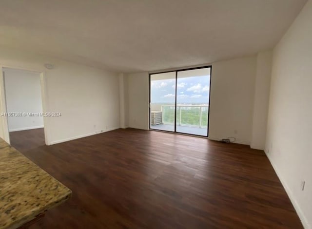 empty room with dark wood-type flooring and expansive windows