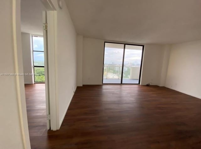 empty room featuring floor to ceiling windows and dark wood-type flooring