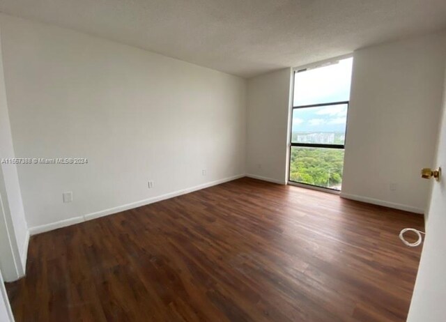 unfurnished room with dark wood-type flooring and expansive windows