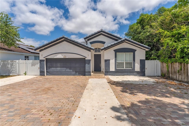 single story home with a garage, a gate, stucco siding, and decorative driveway