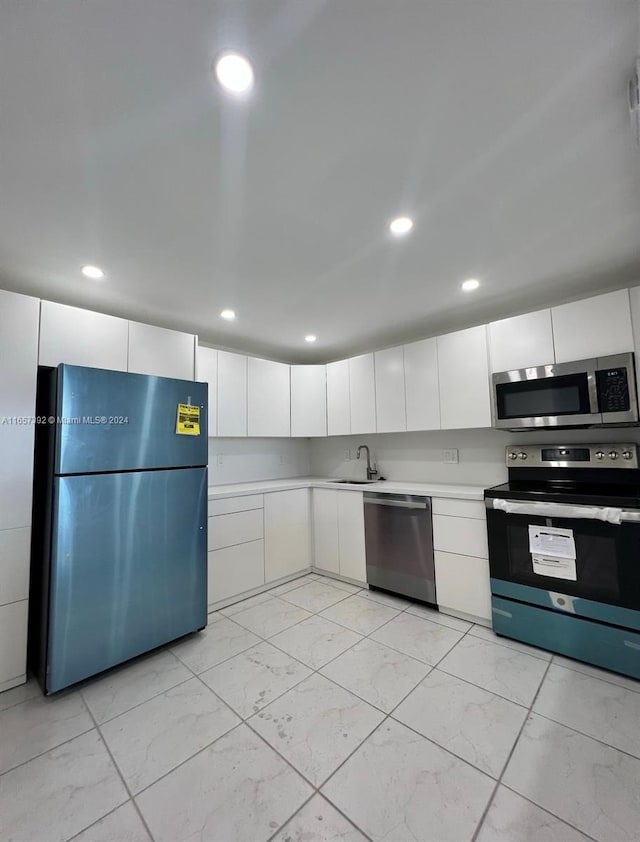 kitchen with stainless steel appliances, white cabinetry, and sink