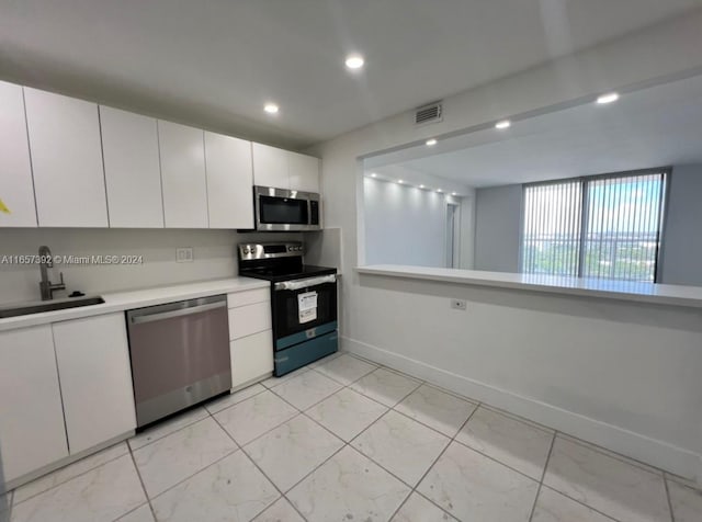13499 Biscayne Blvd Unit 1405, North Miami, FL 33181 - kitchen featuring appliances with stainless steel finishes, a sink, light marble finish flooring, light countertops, and white cabinetry