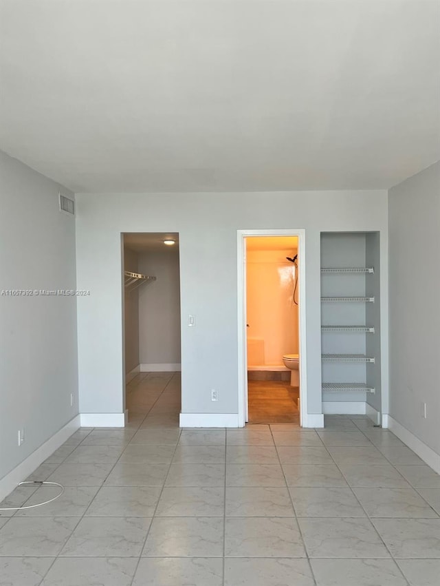 unfurnished bedroom featuring ensuite bath, a spacious closet, and a closet