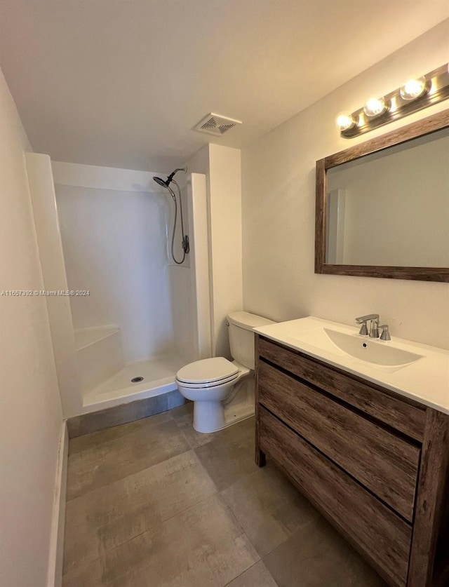 bathroom featuring vanity, toilet, a shower, and tile patterned floors