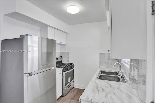 kitchen with white cabinets, hardwood / wood-style flooring, stainless steel appliances, sink, and decorative backsplash