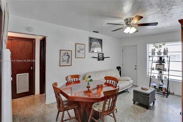 dining space with speckled floor, baseboards, a ceiling fan, and visible vents