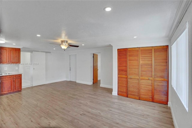 unfurnished living room with ceiling fan, ornamental molding, sink, and light hardwood / wood-style flooring