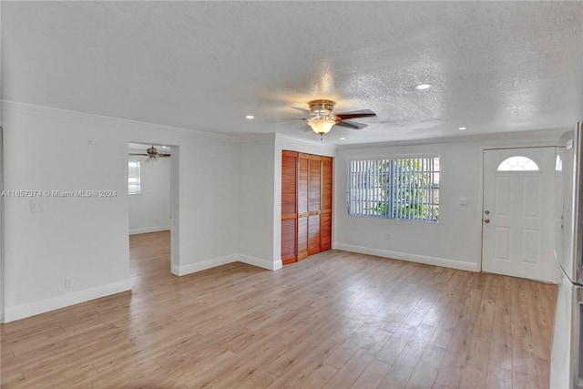 entrance foyer featuring light wood-type flooring, ceiling fan, crown molding, and a textured ceiling