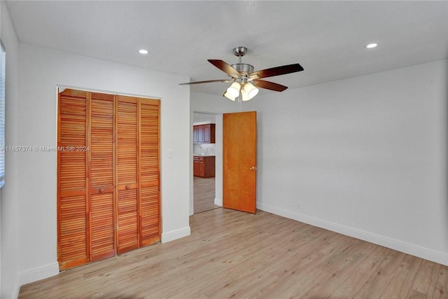 unfurnished bedroom featuring ceiling fan, a closet, and light wood-type flooring