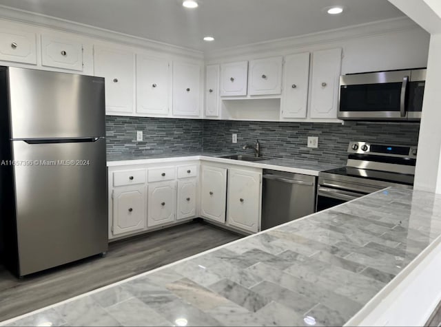 kitchen featuring ornamental molding, tasteful backsplash, stainless steel appliances, sink, and white cabinets