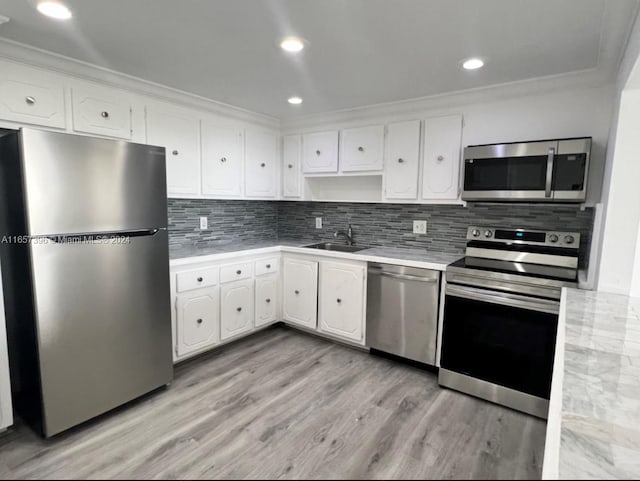 kitchen featuring light wood-type flooring, appliances with stainless steel finishes, white cabinetry, and sink