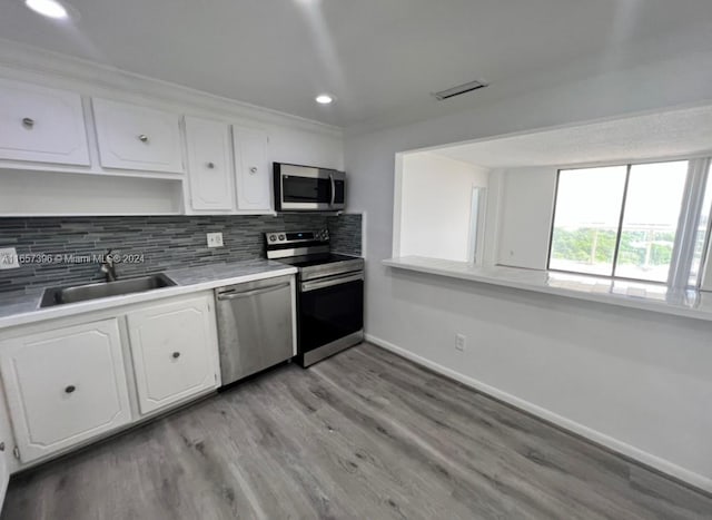 kitchen featuring white cabinetry, light hardwood / wood-style flooring, tasteful backsplash, stainless steel appliances, and sink