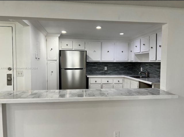 kitchen featuring white cabinets, sink, stainless steel fridge, kitchen peninsula, and tasteful backsplash