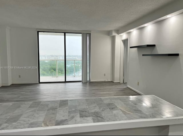13499 Biscayne Blvd Unit 1205, North Miami, FL 33181 - unfurnished living room with a textured ceiling, expansive windows, baseboards, and wood finished floors