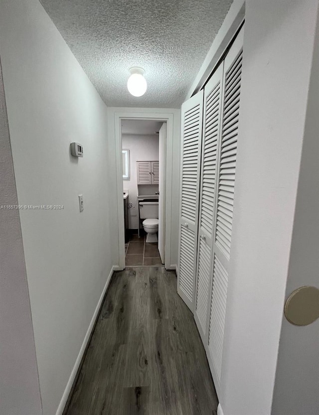 hallway with a textured ceiling and dark hardwood / wood-style floors