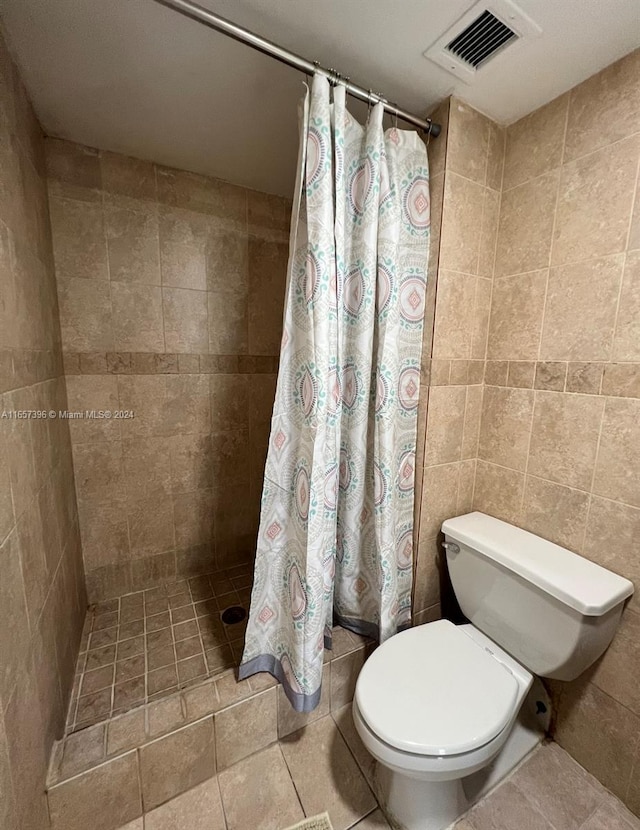 bathroom with tile walls, toilet, curtained shower, and tile patterned flooring