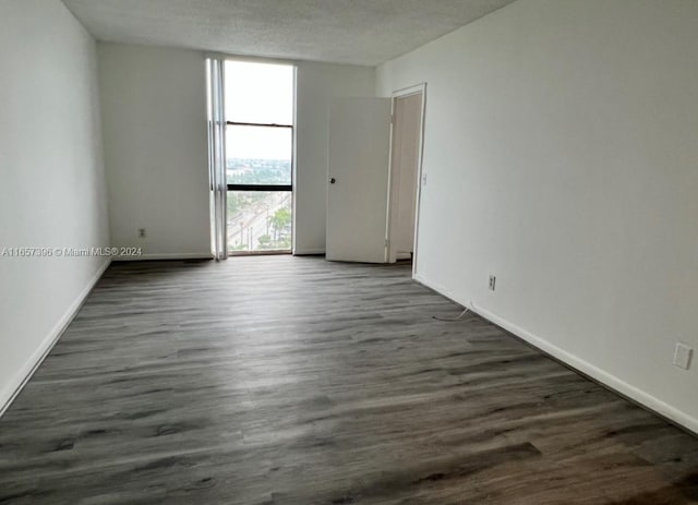 spare room featuring dark wood-type flooring and a textured ceiling