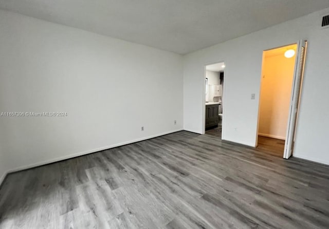 13499 Biscayne Blvd Unit 1205, North Miami, FL 33181 - unfurnished bedroom with dark wood-style floors, baseboards, a walk in closet, and connected bathroom