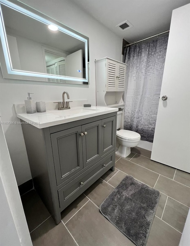 bathroom featuring tile patterned flooring, toilet, walk in shower, and vanity