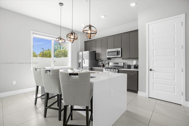 7740 Sandy Ridge Dr Unit 112, Kissimmee, FL 34747 - kitchen with appliances with stainless steel finishes, a kitchen island with sink, a breakfast bar area, baseboards, and decorative light fixtures