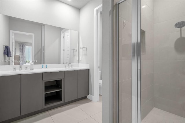 bathroom with tile patterned floors, vanity, toilet, and a shower with door