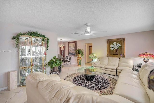 living room featuring ceiling fan, light tile patterned floors, and a textured ceiling