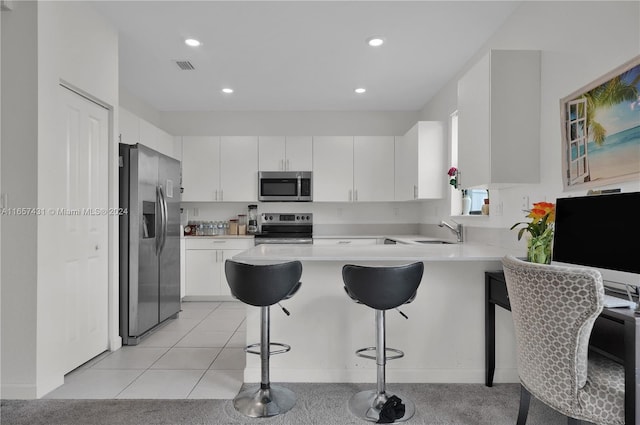 kitchen with a breakfast bar area, stainless steel appliances, kitchen peninsula, and white cabinetry