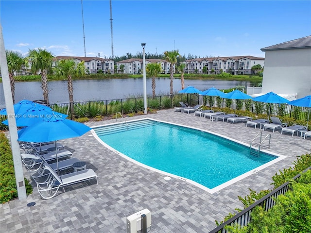 view of pool featuring a water view and a patio