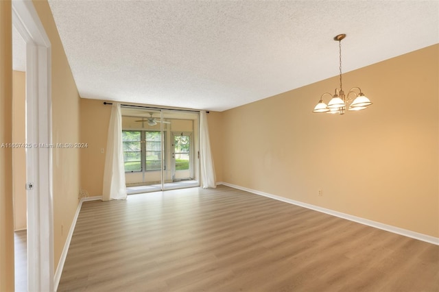 unfurnished room with a textured ceiling, a notable chandelier, and hardwood / wood-style flooring