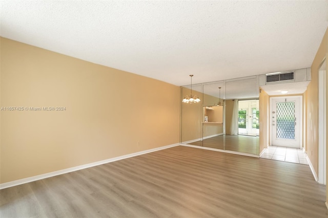 unfurnished room featuring a notable chandelier, a textured ceiling, and hardwood / wood-style flooring