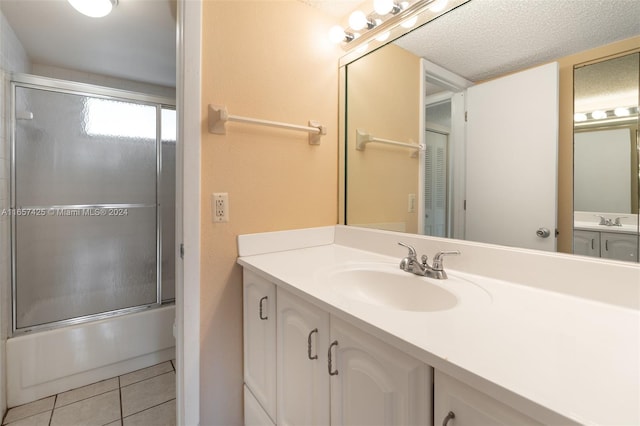 bathroom featuring shower / bath combination with glass door, vanity, a textured ceiling, and tile patterned floors