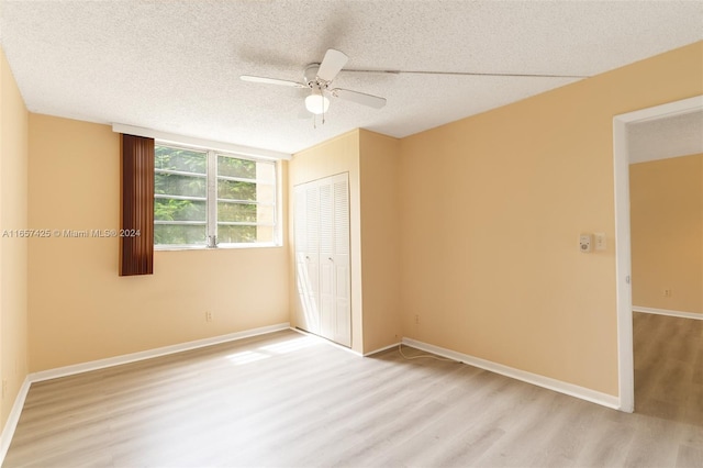 unfurnished bedroom with light wood-type flooring, a textured ceiling, ceiling fan, and a closet