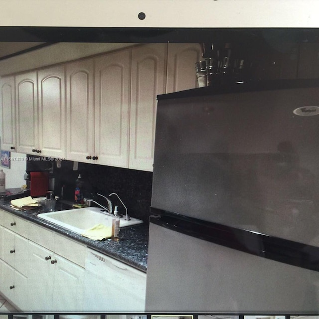 kitchen with white dishwasher, stainless steel refrigerator, and sink