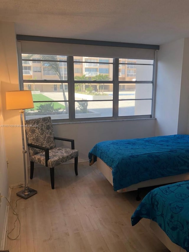 bedroom featuring a textured ceiling, wood-type flooring, and multiple windows