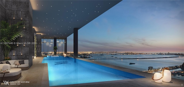 pool at dusk featuring a patio and a water view