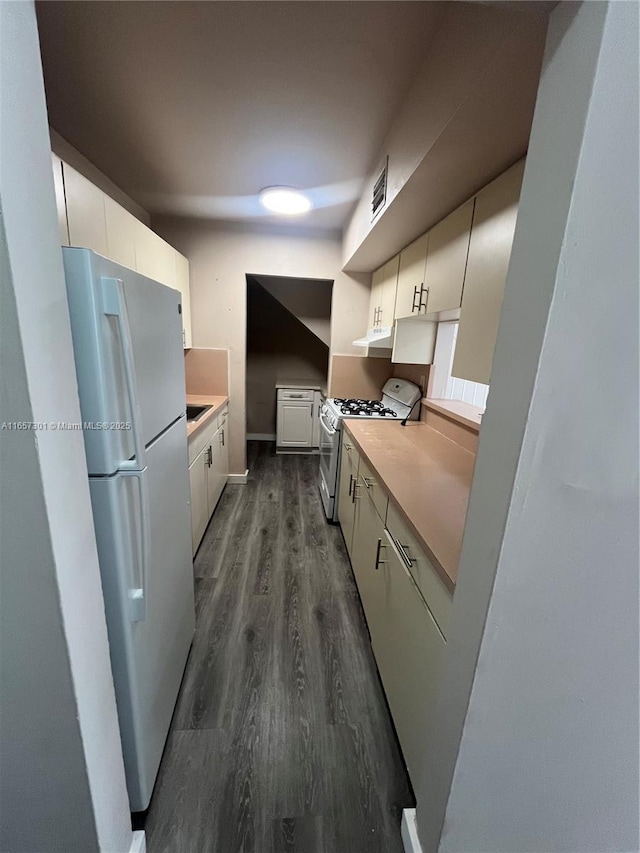 kitchen featuring white cabinets, white gas stove, dark hardwood / wood-style floors, and fridge