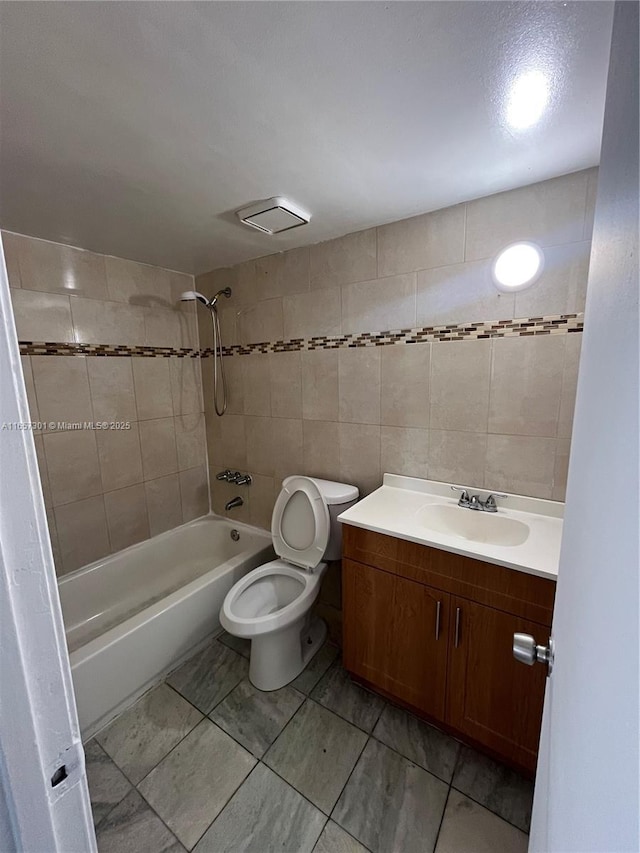 full bathroom with vanity, toilet, tile walls, and tiled shower / bath combo