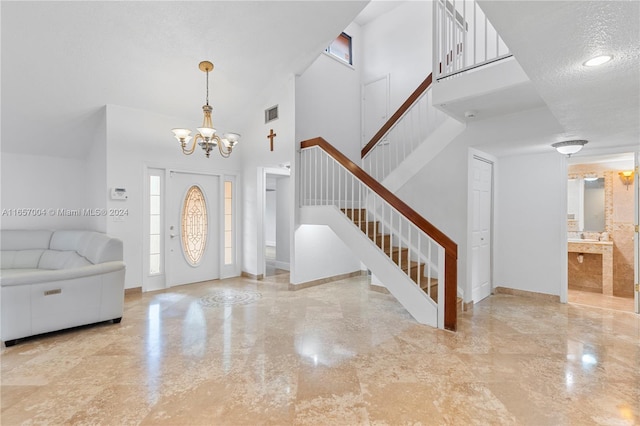 foyer featuring a towering ceiling, a textured ceiling, and a notable chandelier