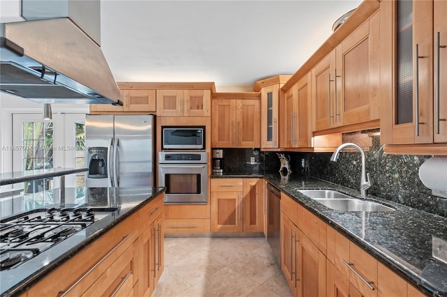 kitchen featuring premium range hood, dark stone countertops, stainless steel appliances, and sink