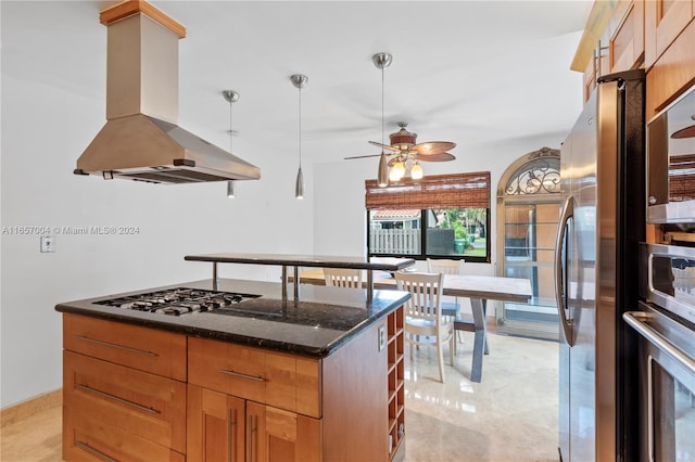 kitchen featuring dark stone countertops, island exhaust hood, a center island, stainless steel appliances, and ceiling fan