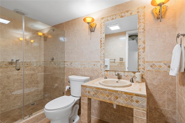 bathroom with a shower with door, a textured ceiling, tile walls, toilet, and sink