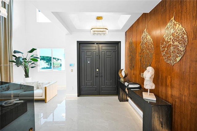 entrance foyer featuring a raised ceiling and wood walls