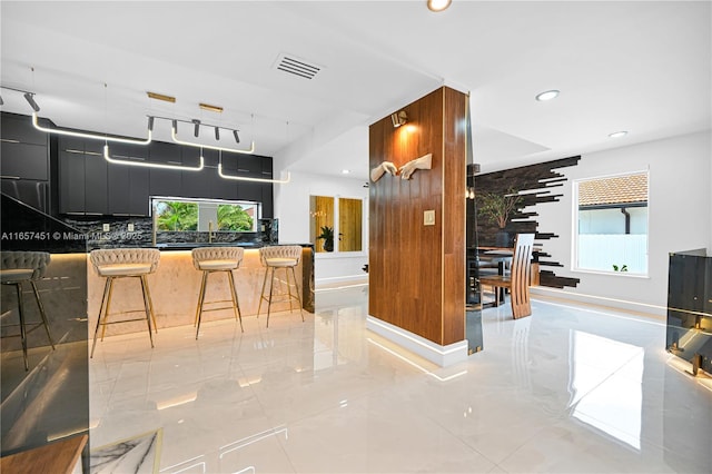 kitchen with tasteful backsplash, a healthy amount of sunlight, and a breakfast bar area