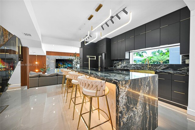 kitchen with a breakfast bar, backsplash, hanging light fixtures, a kitchen island, and high end fridge